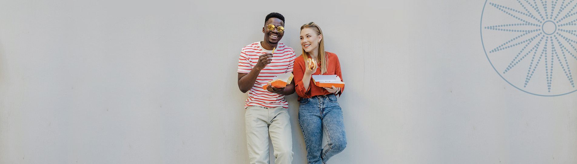 two young friends having take out lunch outside leaning on the wall of a building